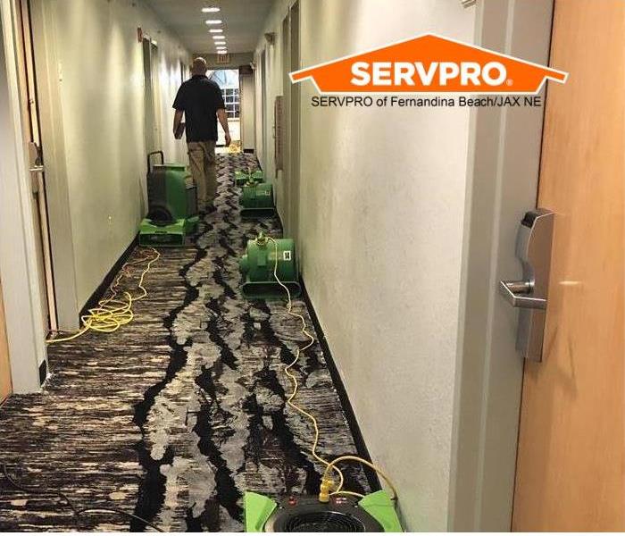 hotel hallway with water damage and fans drying carpet