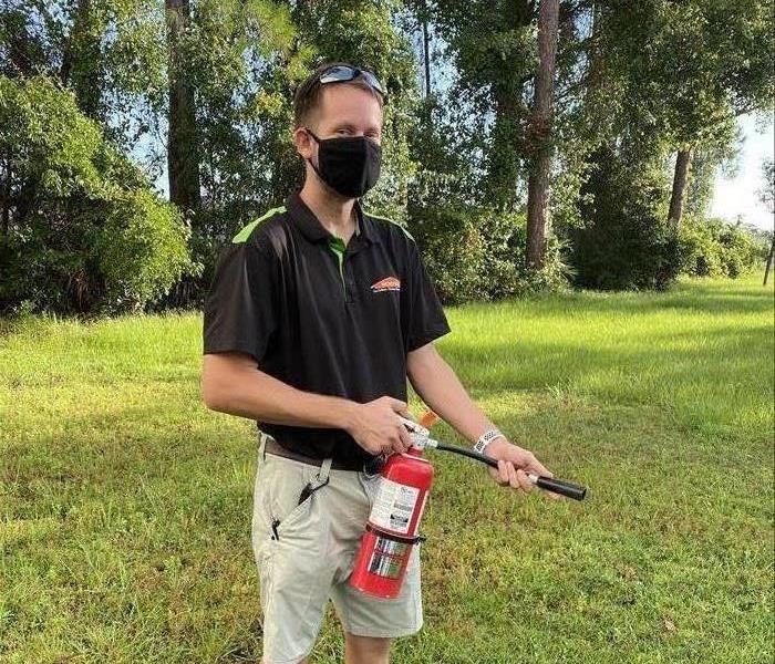  A SERVPRO employee, Josh Hortman, holding a fire extinguisher, demonstrating its proper use.