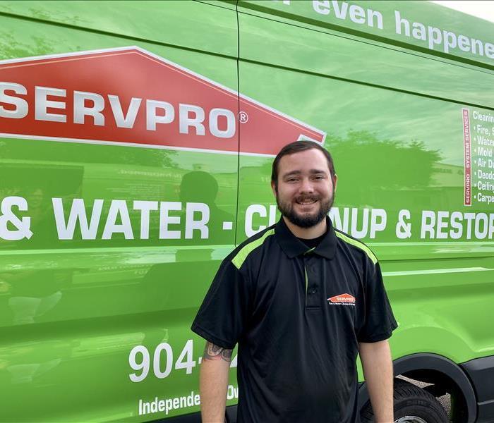 Christon Overly, a dark-haired young man with facial hair, in front of SERVPRO van