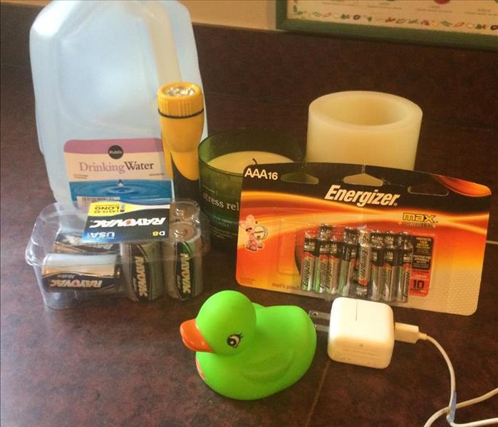 Some ingredients in an emergency kit, including bottled water, flashlight, extra batteries, and phone charger.