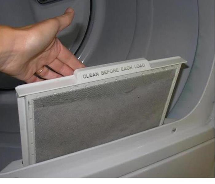 hand pulling lint filter out of a dryer with words "Change before each load."