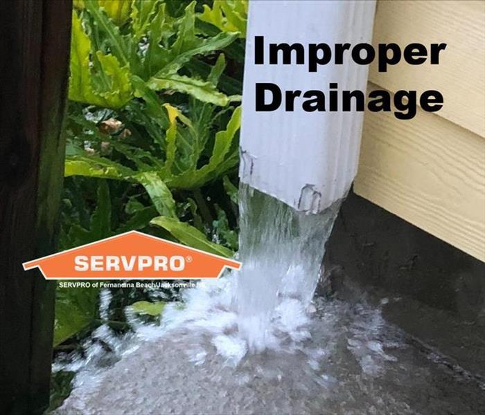 Water pouring out of downspout onto concrete with text “Improper Drainage” and SERVPRO logo.   