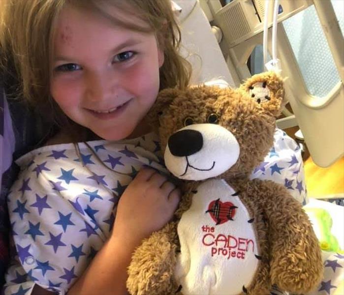 Sick little girl clutching a Caden teddy bear